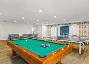 Thumbnail 22 of 34 - A pool table with a green cloth and a white cue ball is in the center of the room.