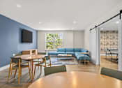 Thumbnail 20 of 34 - A modern living room with a blue wall and a television.