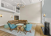 Thumbnail 18 of 34 - A living room with a brown couch, blue chairs, and a fireplace.