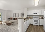 Thumbnail 7 of 34 - A white kitchen with a refrigerator, oven, and microwave.