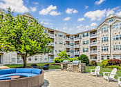 Thumbnail 25 of 34 - A large apartment complex with a courtyard and seating area.