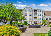 Thumbnail 26 of 34 - A large apartment complex with a courtyard and seating area.