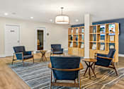 Thumbnail 16 of 34 - A room with blue chairs and a wooden shelf with pictures on it.
