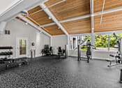 Thumbnail 15 of 34 - A spacious gym with a variety of equipment and a view of trees outside the window.