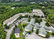 Thumbnail 32 of 34 - A large white building surrounded by trees and a parking lot.