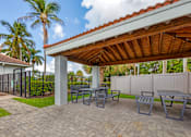 Thumbnail 18 of 33 - A patio with a table and chairs under a roof.