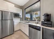 Thumbnail 28 of 33 - A modern kitchen with a stainless steel refrigerator, microwave, and dishwasher.