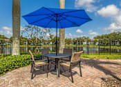 Thumbnail 16 of 33 - A blue umbrella shades a table with chairs around it.