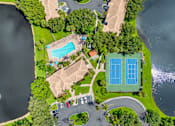 Thumbnail 32 of 33 - A bird's eye view of a park with a tennis court, a swimming pool, and a parking lot.