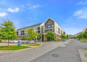 Thumbnail 40 of 42 - A street view of a residential area with apartment buildings and cars parked on the side of the road.