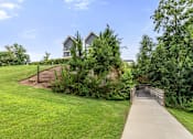 Thumbnail 32 of 42 - A bridge leads to a building surrounded by greenery.