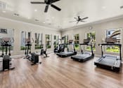 Thumbnail 13 of 38 - A spacious home gym with treadmills, elliptical machines, and a ceiling fan.