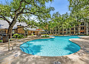 Thumbnail 10 of 38 - A swimming pool surrounded by trees and buildings.