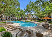 Thumbnail 11 of 38 - A pool surrounded by chairs and trees.