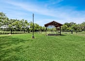 Thumbnail 24 of 38 - A gazebo sits in the middle of a grassy field.