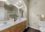 Thumbnail 8 of 38 - A bathroom with a white toilet and a large mirror above a double sink vanity.
