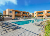 Thumbnail 18 of 29 - A swimming pool is surrounded by sun loungers in front of a building.
