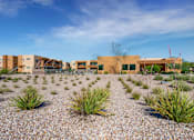 Thumbnail 24 of 29 - A building complex with a gravel courtyard in front.