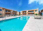 Thumbnail 13 of 29 - A swimming pool in front of a building with a clear blue sky.