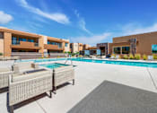 Thumbnail 15 of 29 - A modern outdoor pool area with lounge chairs and a building in the background.