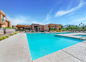 Thumbnail 1 of 29 - A large swimming pool with a diving board and a building in the background.