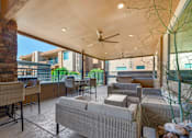 Thumbnail 20 of 29 - A patio with a couch, chairs, and a ceiling fan.