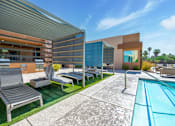 Thumbnail 17 of 29 - A modern outdoor pool area with a lounge chair and a table.