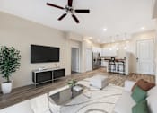 Thumbnail 5 of 29 - A modern living room with a flat screen TV, a coffee table, and a ceiling fan.