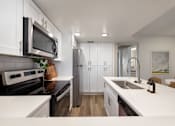 Thumbnail 3 of 37 - A modern kitchen with white cabinets and a black stove top.