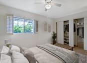Thumbnail 9 of 37 - A bedroom with a large bed and a closet with clothes.