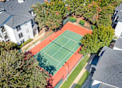 Thumbnail 27 of 36 - A tennis court surrounded by trees and houses.