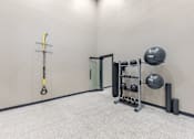 Thumbnail 25 of 36 - A TRX suspension trainer is hanging on a wall in a room with a grey floor.
