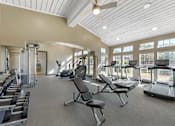 Thumbnail 28 of 36 - A spacious gym with a variety of equipment including treadmills, weights, and a bench.