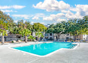 Thumbnail 11 of 36 - A swimming pool surrounded by trees and buildings.