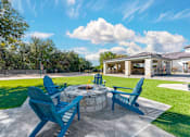 Thumbnail 9 of 36 - A patio with blue chairs and a fire pit.