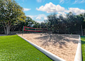 Thumbnail 22 of 36 - A sand volleyball court with a red net and white boundary lines.