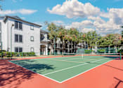 Thumbnail 26 of 36 - A tennis court is located in front of a white building.
