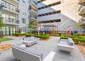 Thumbnail 17 of 27 - A modern outdoor seating area with grey couches and a black fence.