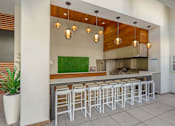 Thumbnail 19 of 27 - A row of white bar stools are arranged in front of a counter.