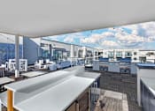 Thumbnail 21 of 27 - A rooftop patio with a white table and chairs.