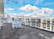 Thumbnail 22 of 27 - A balcony with a table and chairs overlooks a row of buildings.