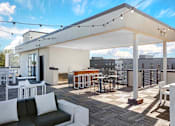 Thumbnail 20 of 27 - A white patio with a black couch and a table with chairs.