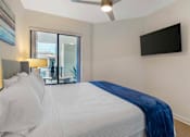 Thumbnail 6 of 27 - A bedroom with a large bed and a flat screen TV mounted on the wall.