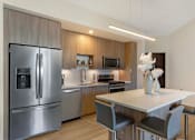 Thumbnail 1 of 27 - A modern kitchen with a refrigerator, sink, and dining table.