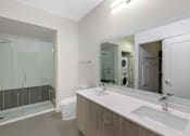 Thumbnail 11 of 27 - A modern bathroom with a glass shower door and a white sink.