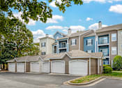 Thumbnail 16 of 27 - A row of apartments with detached garages in front of a tree.