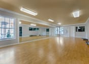 Thumbnail 19 of 28 - A spacious room with wooden floors and large windows.