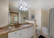 Thumbnail 7 of 28 - A full bathroom with a granite countertop and a white vanity.