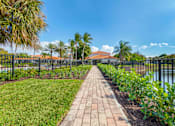 Thumbnail 16 of 28 - A walkway with a metal fence and green plants on both sides.