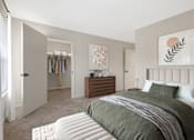 Thumbnail 2 of 26 - A bedroom with a large bed and a wooden dresser at Residences at Westborough Station, Westborough, MA